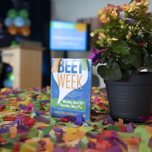 Beet Week poster with a flower post and petal scattered on the table.
