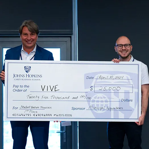 two people holding a large check