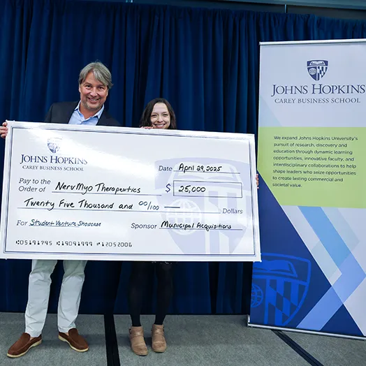 jhu carey student receiving large check on stage for winning showcase