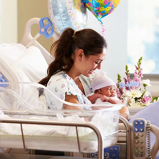 Joyful mom with new born in a hospital bed