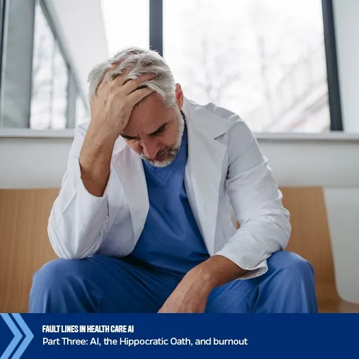 A stressed male doctor sits with his head in his hand